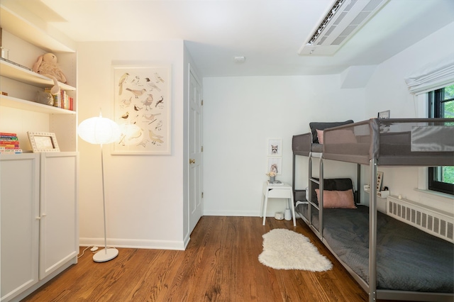 bedroom with radiator heating unit and hardwood / wood-style floors