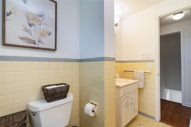 bathroom with vanity, toilet, tile patterned flooring, and tile walls