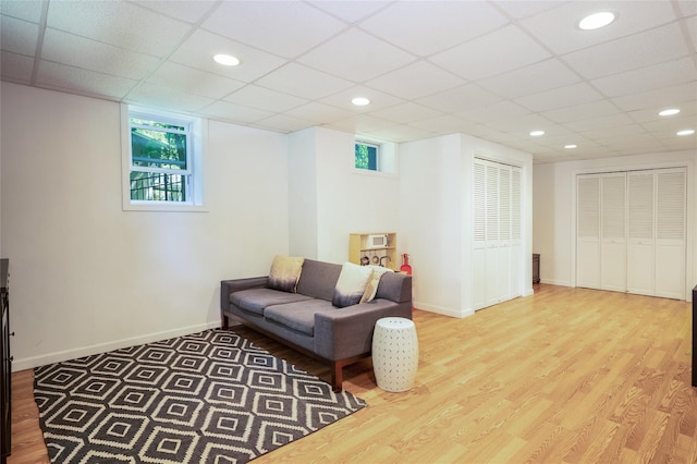 living room featuring wood-type flooring, a healthy amount of sunlight, and a drop ceiling