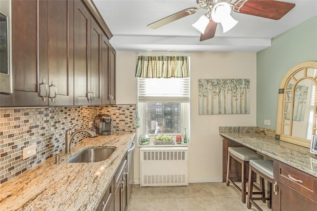 kitchen featuring light stone counters, sink, decorative backsplash, and dark brown cabinets