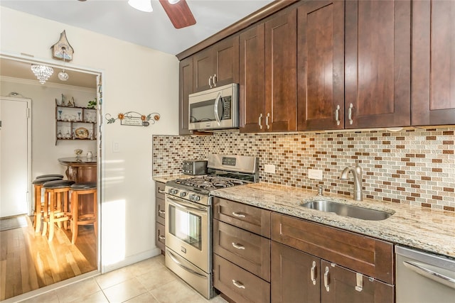 kitchen with sink, light tile patterned floors, ceiling fan, stainless steel appliances, and light stone countertops