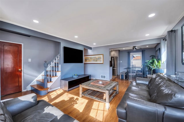 living room featuring ornamental molding, light hardwood / wood-style floors, and ceiling fan