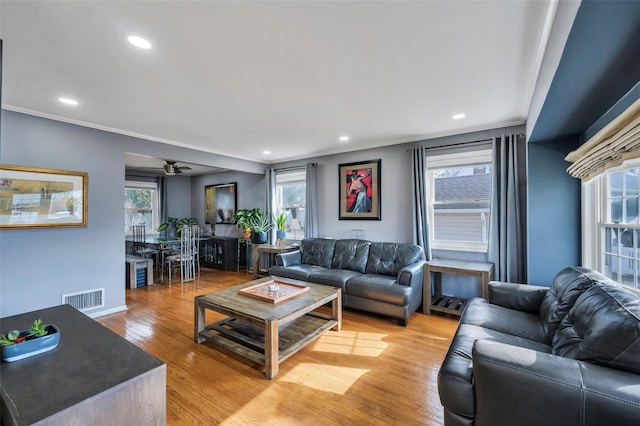 living room with crown molding, a wealth of natural light, and light hardwood / wood-style flooring