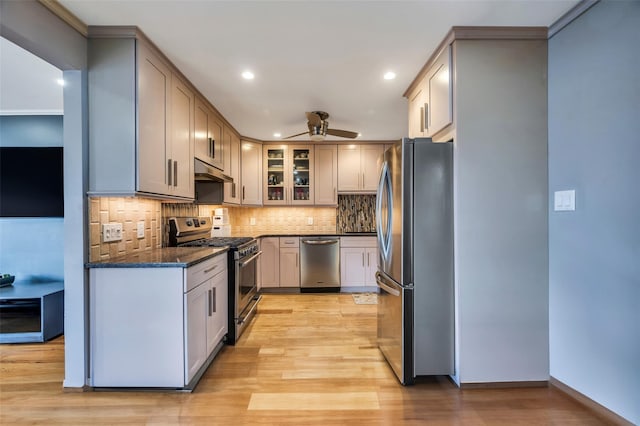 kitchen featuring stainless steel appliances, tasteful backsplash, light hardwood / wood-style flooring, and dark stone counters