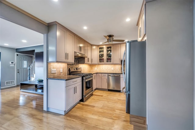 kitchen with stainless steel appliances, dark stone countertops, backsplash, and light hardwood / wood-style floors