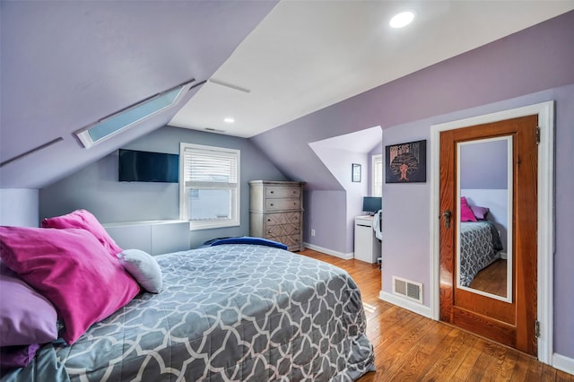 bedroom with wood-type flooring and lofted ceiling with skylight