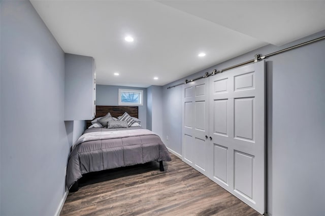 bedroom featuring dark hardwood / wood-style flooring and a barn door