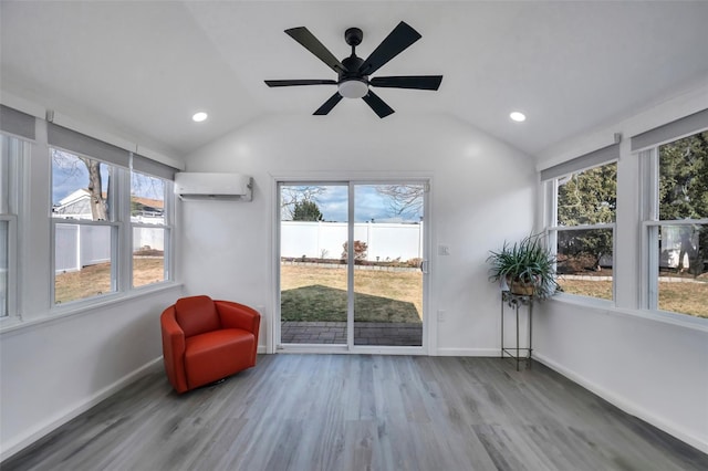 living area featuring a wall mounted air conditioner, vaulted ceiling, hardwood / wood-style floors, and ceiling fan