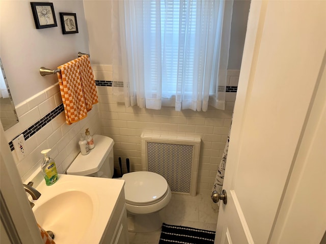 bathroom featuring vanity, radiator heating unit, tile walls, and toilet