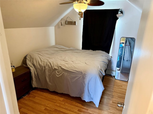 bedroom featuring wood-type flooring, lofted ceiling, a baseboard heating unit, and ceiling fan