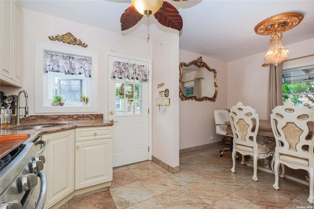 kitchen featuring ceiling fan with notable chandelier, stainless steel range, and sink