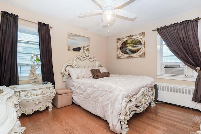 bedroom with cooling unit, ceiling fan, radiator, and light wood-type flooring