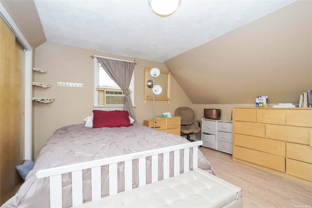 bedroom featuring lofted ceiling, cooling unit, and light hardwood / wood-style flooring