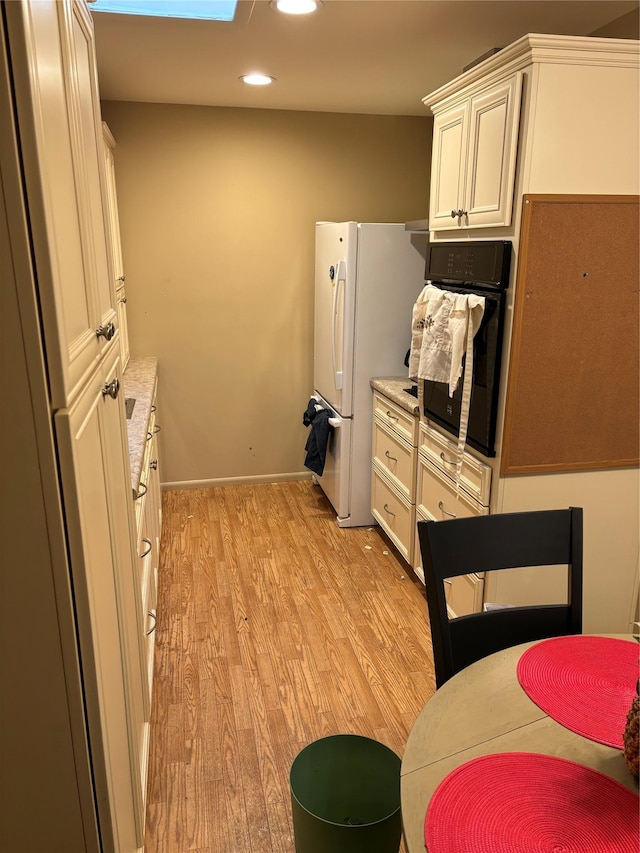 kitchen featuring oven, white fridge, and light wood-type flooring