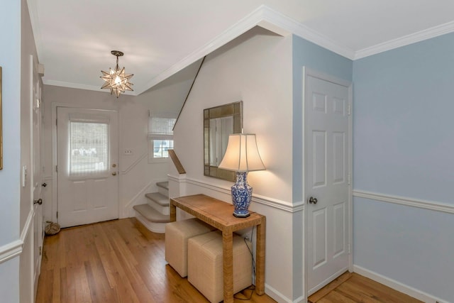 foyer entrance with an inviting chandelier, ornamental molding, and light hardwood / wood-style flooring