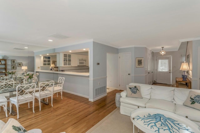 living room featuring crown molding and light hardwood / wood-style flooring