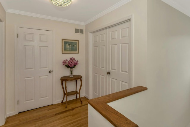 corridor with ornamental molding and light hardwood / wood-style flooring