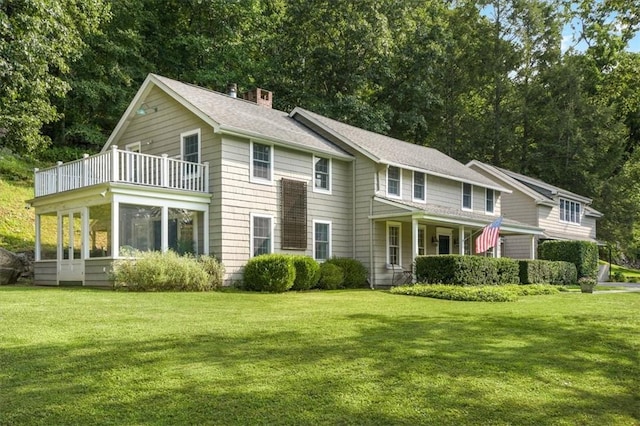 view of front of property with a balcony, a sunroom, and a front yard