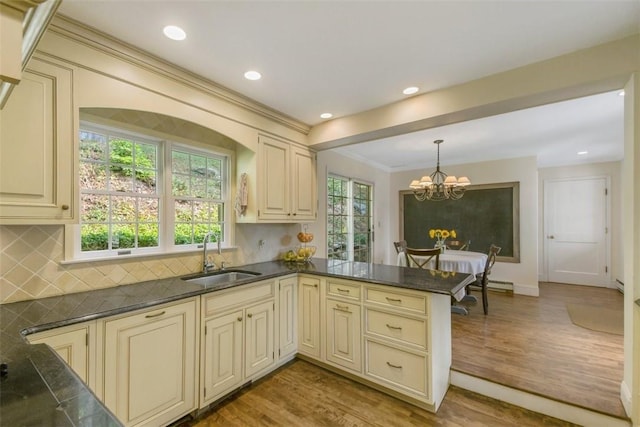 kitchen featuring sink, light hardwood / wood-style flooring, kitchen peninsula, pendant lighting, and cream cabinets