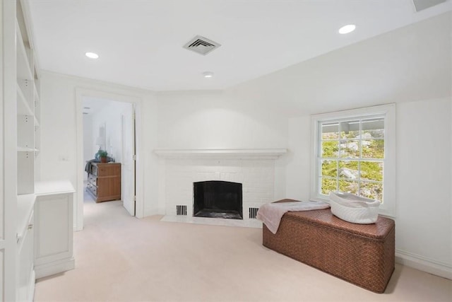 living area featuring light carpet and a fireplace