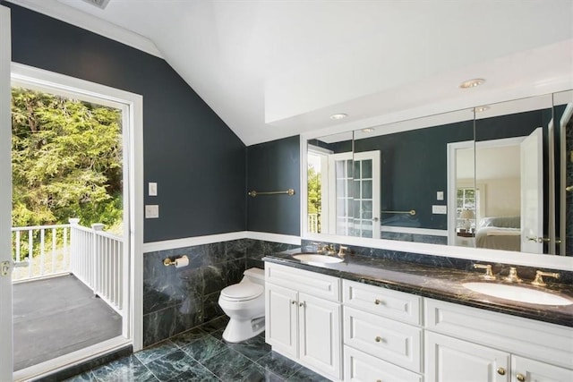 bathroom with vanity, vaulted ceiling, tile walls, and toilet