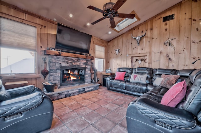 tiled living room with lofted ceiling, a fireplace, wooden walls, and ceiling fan