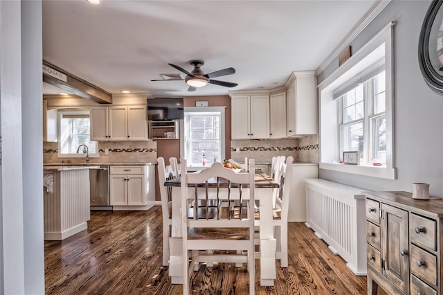 dining space with ceiling fan, dark hardwood / wood-style flooring, radiator, and sink