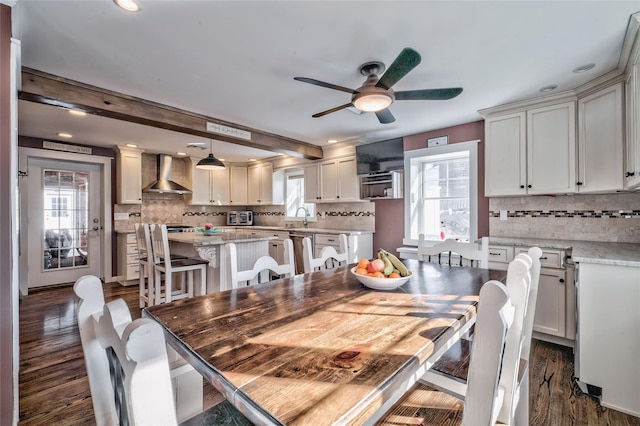 dining space featuring beamed ceiling, ceiling fan, dark wood-type flooring, and sink