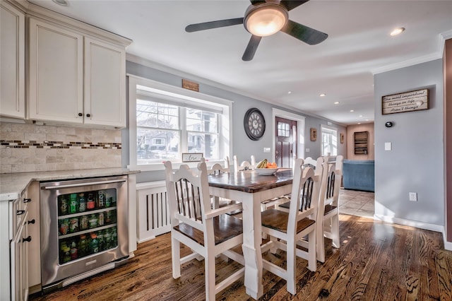 dining area featuring a wealth of natural light, ornamental molding, and beverage cooler