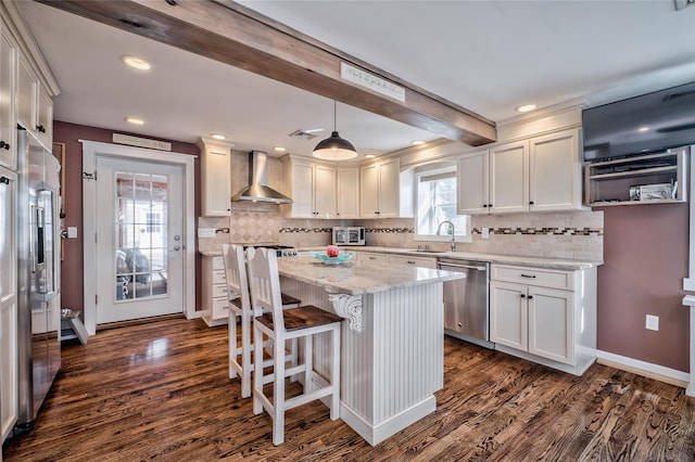 kitchen with pendant lighting, wall chimney range hood, sink, dishwasher, and white cabinets