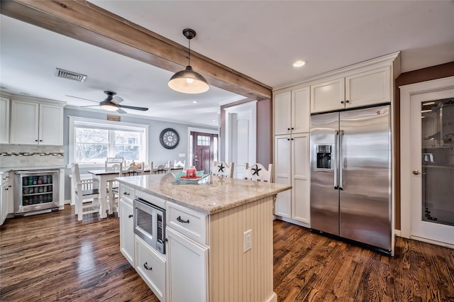 kitchen with pendant lighting, dark wood-type flooring, appliances with stainless steel finishes, wine cooler, and light stone countertops