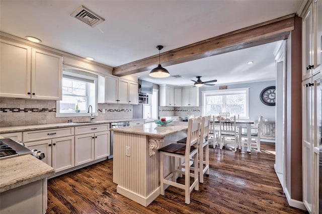 kitchen with white cabinetry, decorative light fixtures, light stone countertops, and a kitchen island