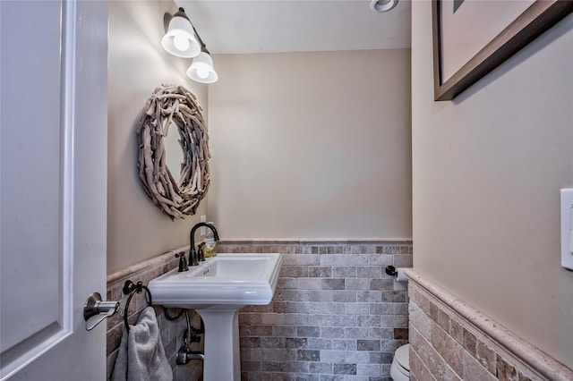 bathroom featuring toilet and tile walls