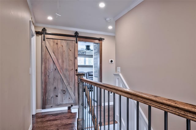 interior space with ornamental molding, a barn door, and hardwood / wood-style floors