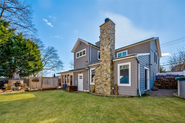 rear view of property featuring a fireplace and a lawn