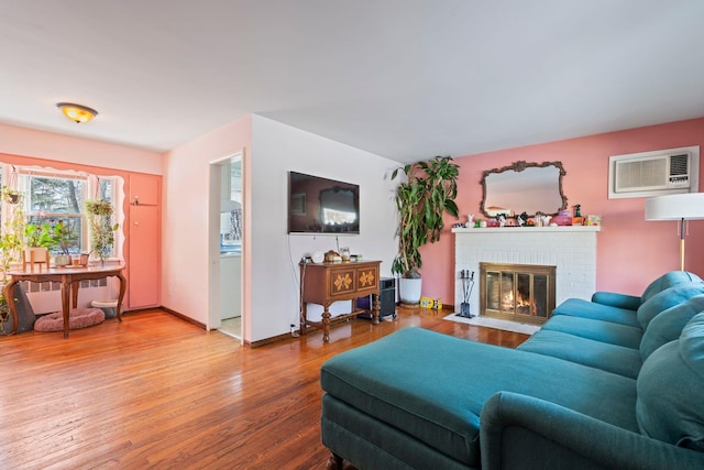 living room featuring hardwood / wood-style flooring, a wall mounted air conditioner, and a brick fireplace