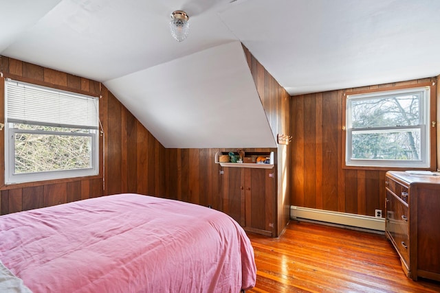 bedroom with a baseboard radiator, light hardwood / wood-style floors, vaulted ceiling, and wood walls