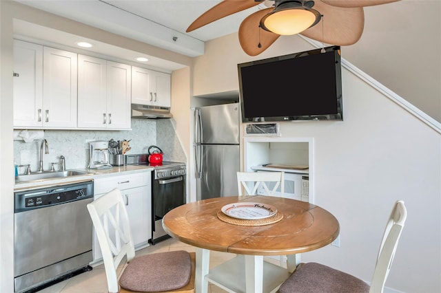 kitchen featuring appliances with stainless steel finishes, sink, white cabinets, decorative backsplash, and ceiling fan