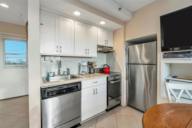 kitchen with sink, light tile patterned floors, appliances with stainless steel finishes, white cabinetry, and tasteful backsplash