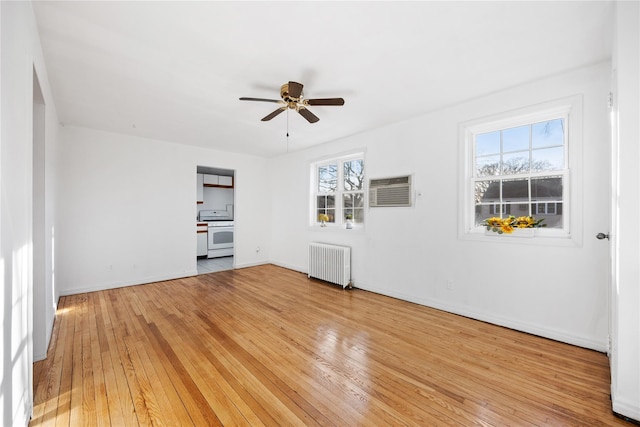 spare room featuring ceiling fan, radiator heating unit, a wall mounted air conditioner, and light hardwood / wood-style flooring