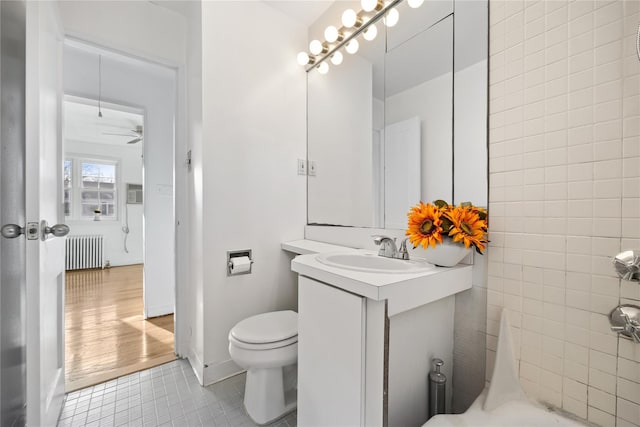 bathroom featuring radiator, tile walls, vanity, toilet, and tile patterned floors