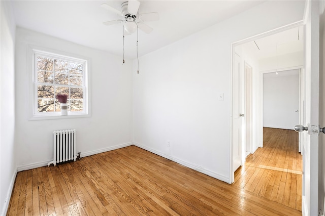 spare room featuring ceiling fan, radiator heating unit, and light hardwood / wood-style floors