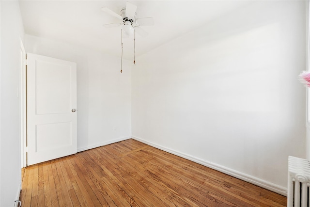 unfurnished room featuring hardwood / wood-style flooring, ceiling fan, and radiator