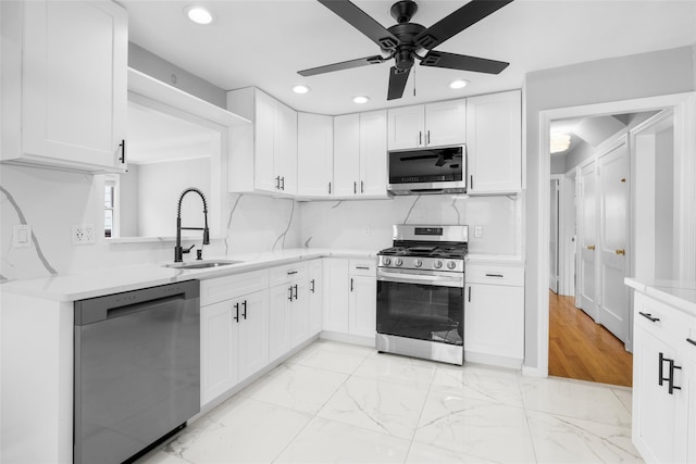 kitchen with marble finish floor, stainless steel appliances, a sink, and light countertops