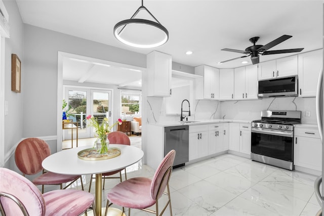 kitchen featuring marble finish floor, stainless steel appliances, tasteful backsplash, light countertops, and a sink