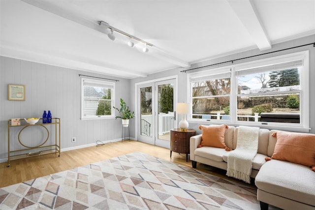 sunroom / solarium featuring track lighting and beamed ceiling