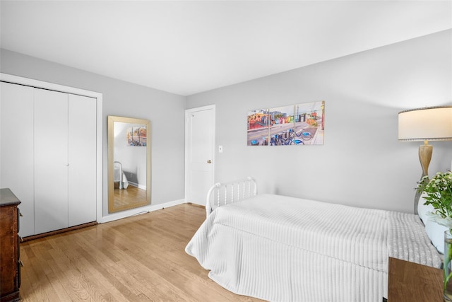 bedroom with baseboards, a closet, and light wood-style floors