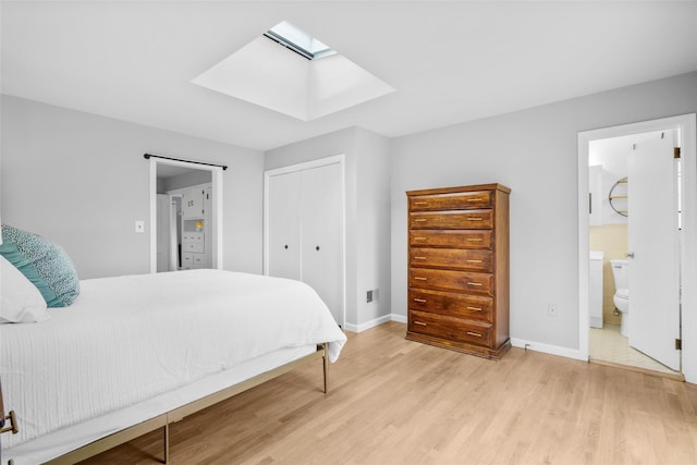 bedroom with a skylight, a closet, light wood-style flooring, and baseboards