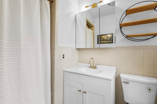 bathroom featuring wainscoting, toilet, tile walls, and vanity