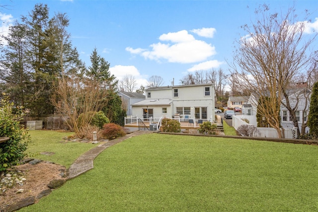 back of property with a fenced backyard, a lawn, and a deck